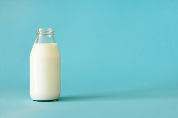 Fresh milk in glass bottle isolated on blue background with place for text. Front view