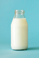 Fresh farm milk in glass bottle isolated on blue background. Close-up. Bottle is full of milk. Front view