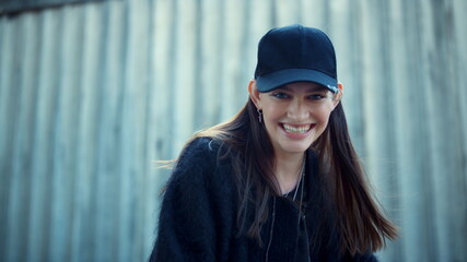 Happy girl posing at camera on urban street. Cheerful woman laughing outdoors