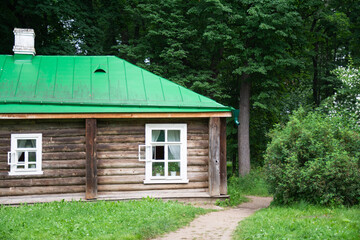 Fototapeta na wymiar old wooden house with green metal roof on forest background