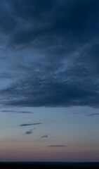 Rain in the forest. Storm clouds against a blue sky. The sun is hidden. Panorama. Tragic gloomy sky. Fantastic skies on the planet earth. Twilight, nightfall.