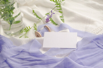 Wedding mockup with violet flowers and delicate silk ribbons on a white background. Greeting card or wedding invitation with jagged edges