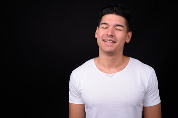 Young handsome multi ethnic man against black background