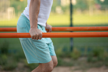 A man does push-UPS on the bars on the street close-up