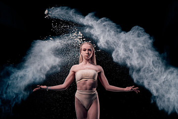 dancing girl in flour (powder). Black studio. Ballet dance.