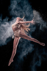 Fototapeta na wymiar dancing girl in flour (powder). Black studio. Ballet dance.