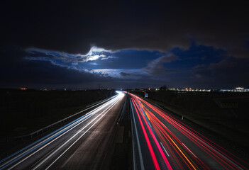 Eine Autobahn bei Nacht mit den Lichtern der Autos. Dabei bilden die Autoscheinwerfer Lichtlinien.