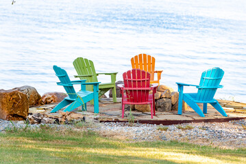 Adirondack chairs on a flagstone deck surrounding a firepit overlooking a body of water.