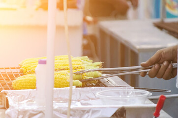 Street seller flipping corn on grill
