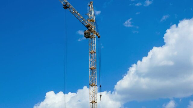The work of a construction crane against the background of the cloudy sky time laps. Construction site process working time laps
