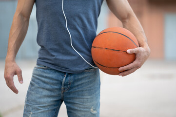 Man stands with a basketball on the street close up