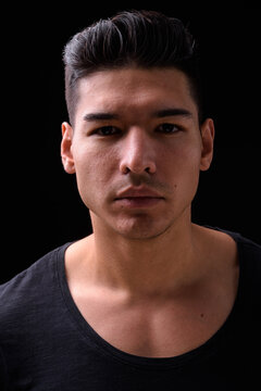 Young handsome multi ethnic man against black background