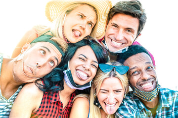 Multiracial friends taking selfie with open face masks - New normal friendship concept with young people having fun together - Multicolor sunshine filter with focus on afroamerican girl in middle