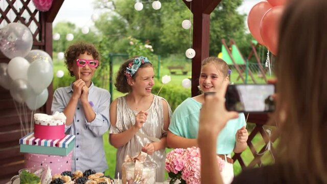 An unrecognizable woman takes pictures of children at the children's birthday party. Birthday party, happy childhood, catering agency