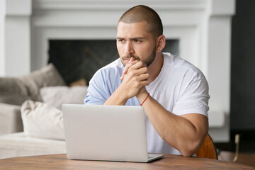 a serious man with a beard works at a laptop and gestures with his hands