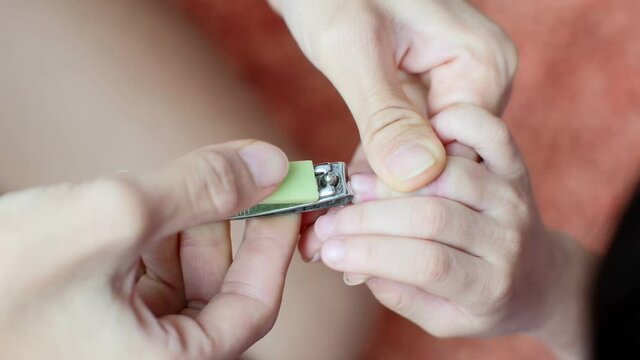 Woman using nail clipper cutting nails of kids .