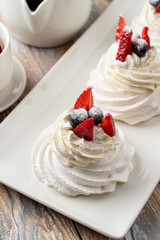 Close up of meringue pavlova dessert, fluffy and elegant, decorated with blueberries and strawberries