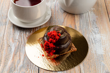 One glazed truffle candy on a golden plate with strawberry crumbs as a decoration