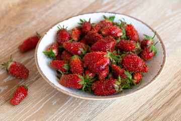 bowl with ripe strawberries on light wooden table
