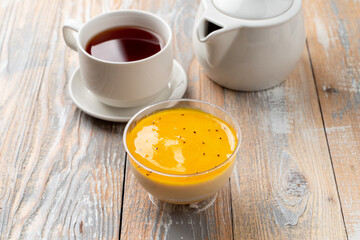 Mango panna cotta with cream and mango puree on wooden table in a plastic cup
