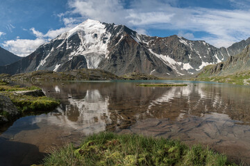 Naklejka na ściany i meble Glacier on a mountain peak. The mystical face of a ghost is reflected in the lake. Altai, Russia.
