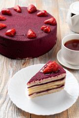 A slice of purple red velvet torte with fresh strawberries on old wooden table