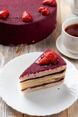 Close up of red velvet strawberry cake on white elegant plate, layered strawberry torte with beautiful purple icing