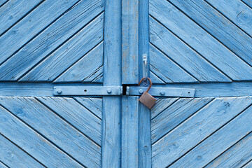 Old blue wooden barn doors with an open rusty lock.