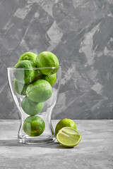 glass vase full of green limes on concrete background