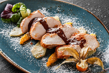Turkey meat steak with caramelized fruit and chocolate chili sauce in plate on dark stone background. Hot Meat Dishes