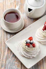 Meringue anna pavlova meringue dessert, topped with blueberry and strawberry on wooden table in an italian cafe