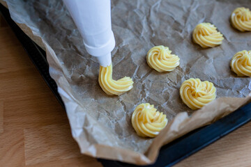 Bignè alla panna all'italiana. Profiteroles al cioccolato fondente. Preparazione a mano prima della cottura al forno.