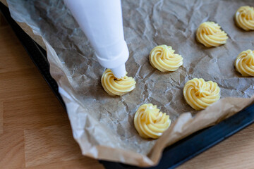 Bignè alla panna all'italiana. Profiteroles al cioccolato fondente. Preparazione a mano prima della cottura al forno.