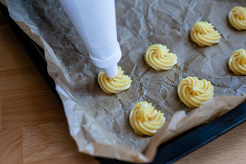 Bignè alla panna all'italiana. Profiteroles al cioccolato fondente. Preparazione a mano prima della cottura al forno.