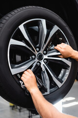 cropped view of technician touching wheel disk while fixing car