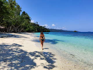 Young woman walking on paradise beach in Raja Ampat,  Papua, Indonesia