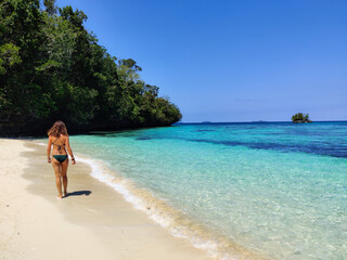 Young woman walking on paradise beach in Raja Ampat,  Papua, Indonesia