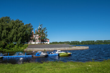 A pier with boats in Kamenny Brook and the Church of Demetrius on Blood.