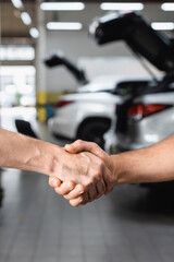 Selective focus of handshake gesture of men at service station