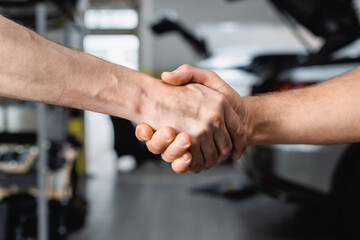 Selective focus of handshake gesture of men at service station