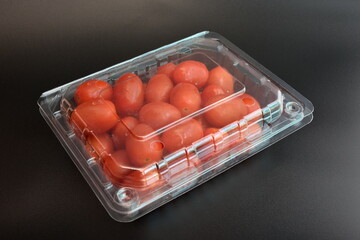 Tomatoes in plastic packaging placed on a black background