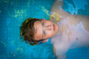 yong man with amazing blue eyes in swimming pool ,enjoying his holiday . top view
