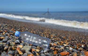 Discarded plastic drink bottle washed up on pebble beach