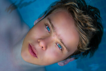 yong man with amazing blue eyes in swimming pool ,enjoying his holiday . top view