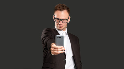 Social media addiction. Modern technology. Confident business man taking selfie on phone isolated on black copy space blur background. Online communication. Mobile app.