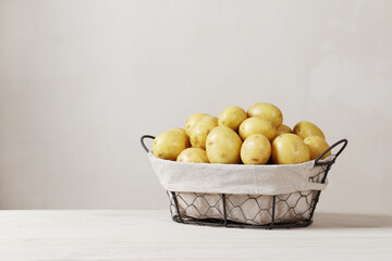 Basket full of fresh, young potatoes on a wooden table with place for text.