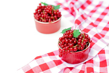 Red currant berries in a cocotte bowl on a white plate with a kitchen towel. Natural vitamins concept. Flat lay.