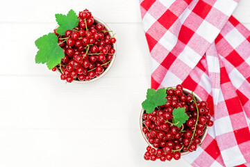 Red currant berries in a cocotte bowl on a white plate with a kitchen towel. Natural vitamins concept. Flat lay.