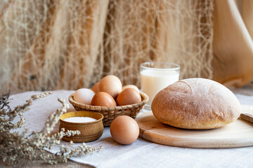 Bread eggs salt and milk on wooden plates on a background in warm colors