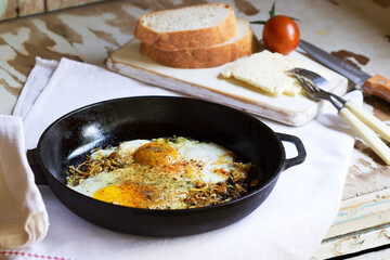 Fried eggs with onions and spices in a cast iron skillet.